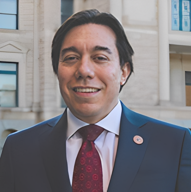 Man in suit smiling near building facade.