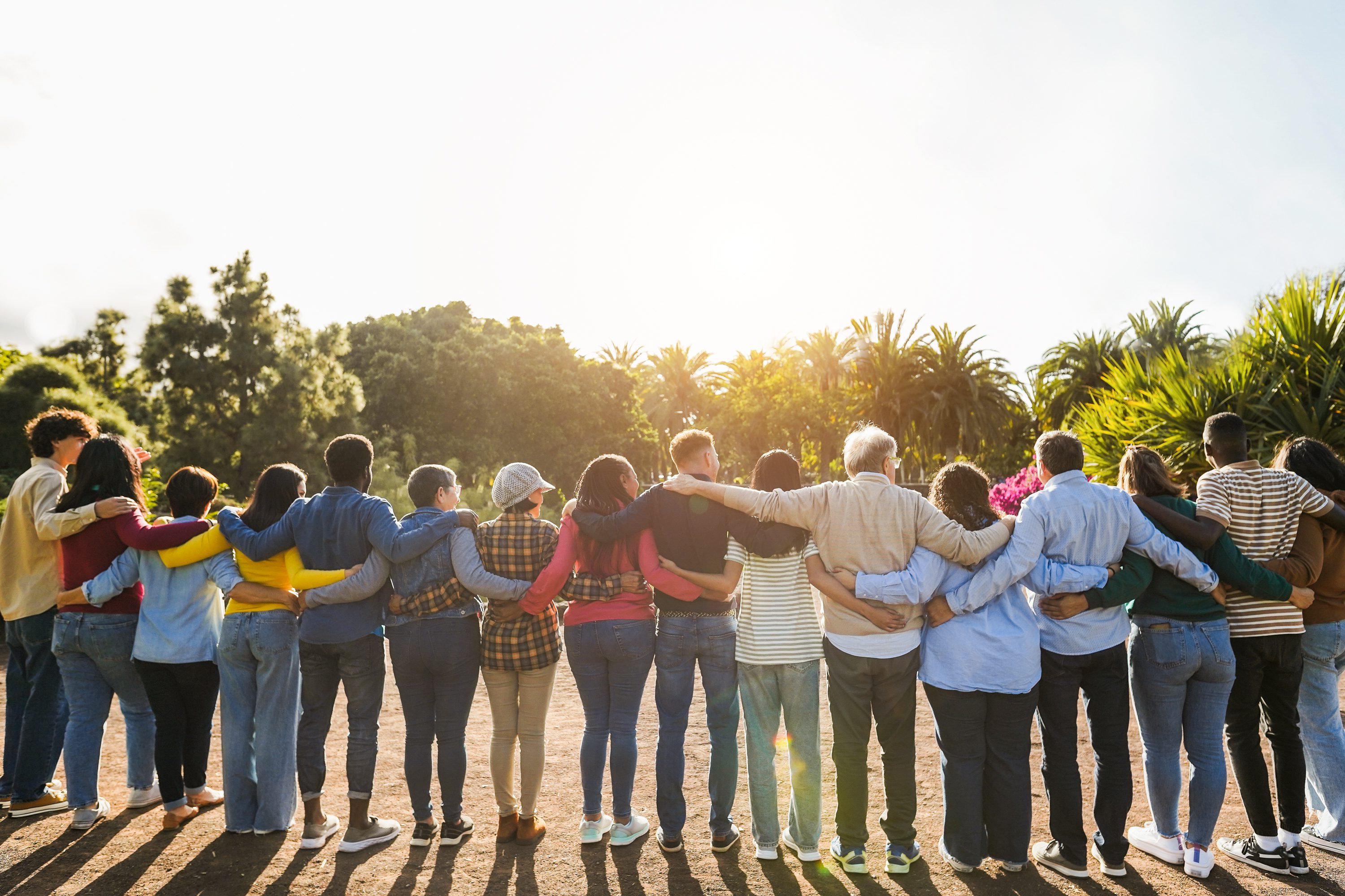 Diverse group embracing in a sunny park.