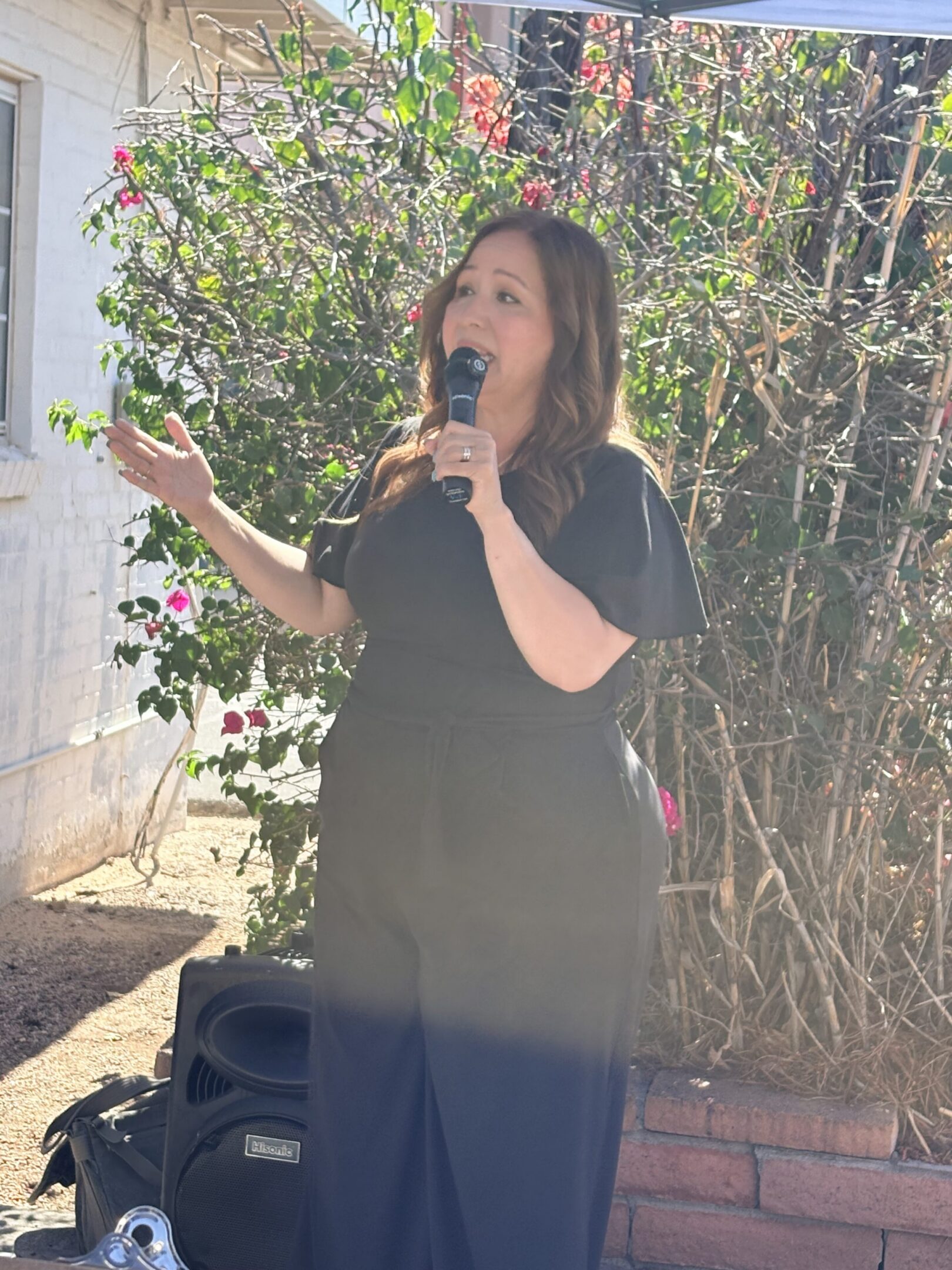 Woman singing with microphone outdoors.