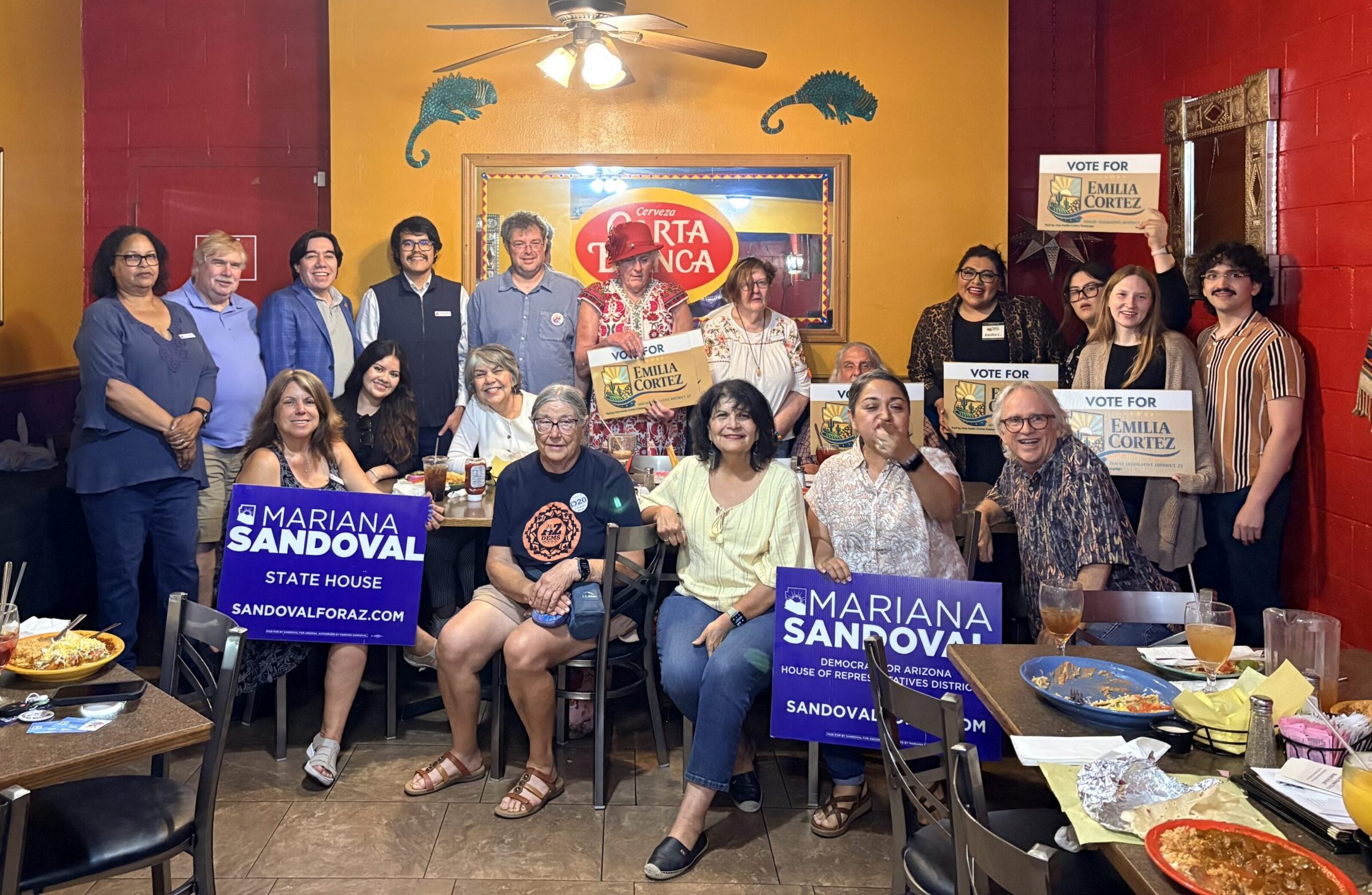 Group posing with campaign signs indoors.