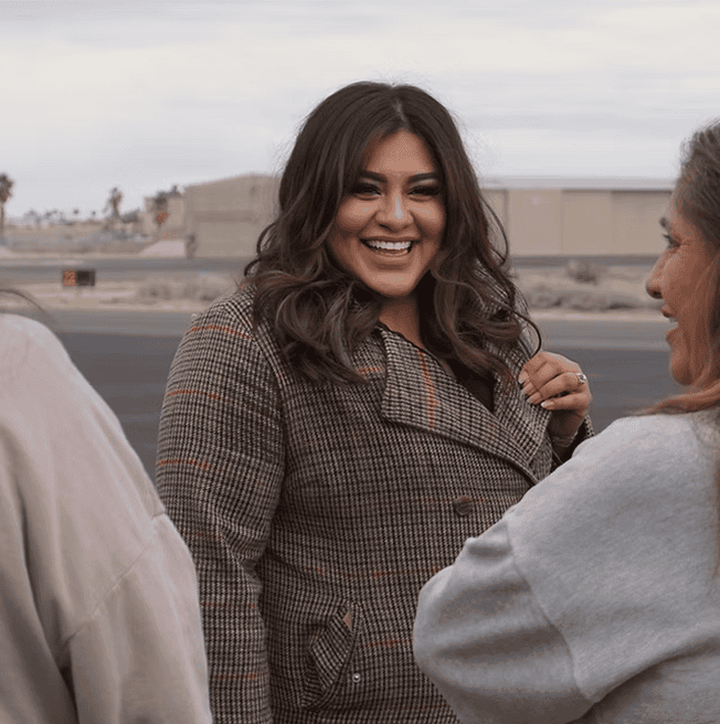 Smiling woman in a plaid coat outdoors.