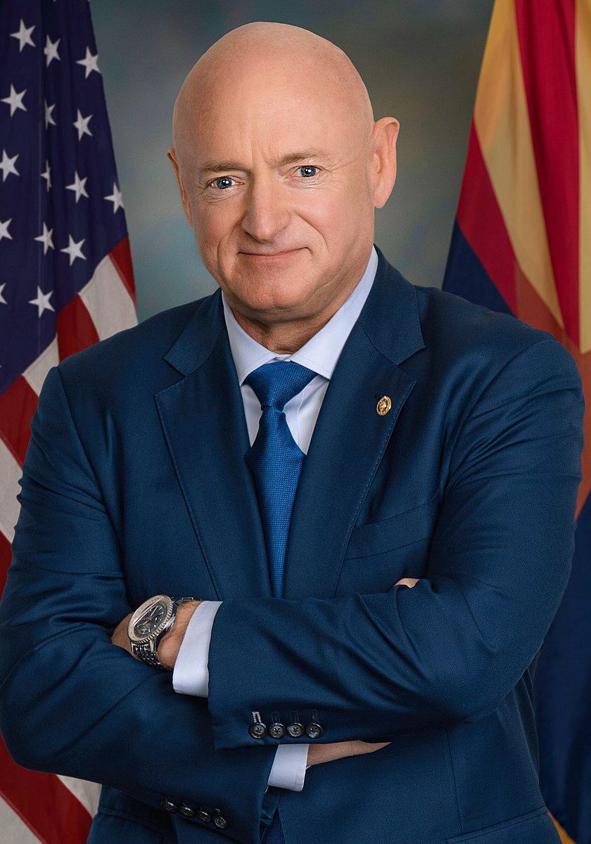 Man in suit with flags in background.