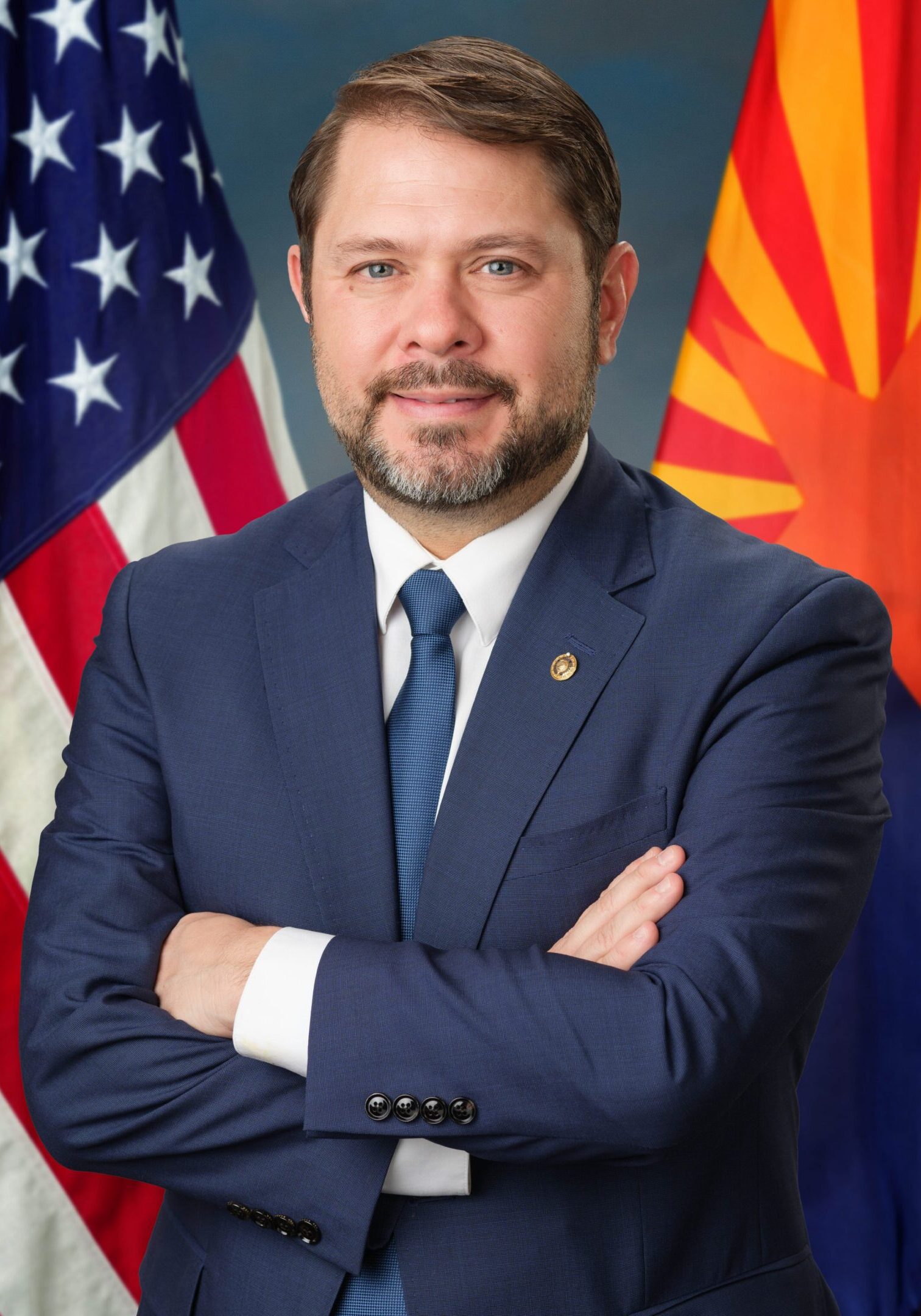 Man in suit with American and Arizona flags.